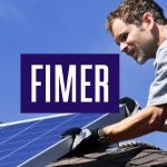一名男子在屋顶安装带有Fimer标识的太阳能电池板