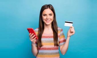 年轻女子拿着手机和银行卡在蓝色背景下