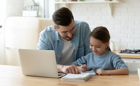 父亲在笔记本电脑前辅导女儿做作业