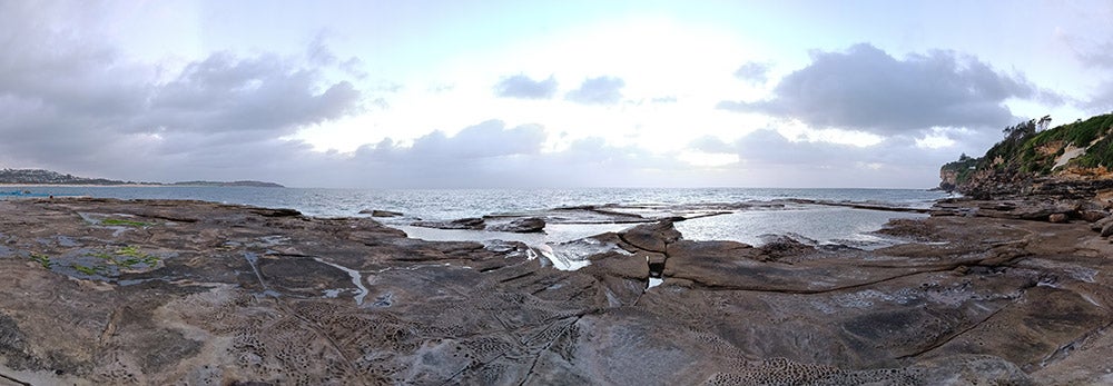 全景拍摄的岩石池和日出在海洋