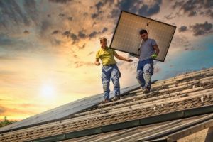 两名男子在屋顶上搬运太阳能电池板