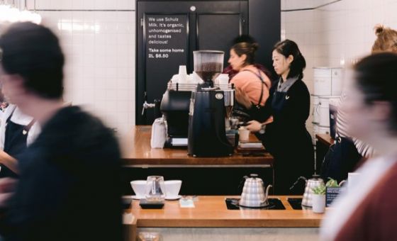 墨尔本一家咖啡馆的咖啡师正在为坐着的顾客煮咖啡