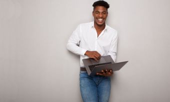 微笑的年轻黑人男子拿着笔记本电脑