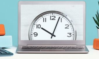 蓝色桌子上的笔记本电脑屏幕上的时钟带装饰品。