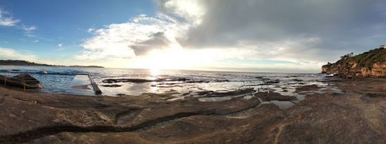 日出时海洋和岩石池的全景
