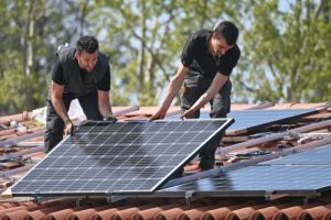 两个太阳能安装工人将电池板固定在屋顶上
