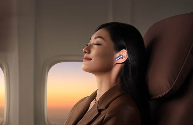 女子在飞机上戴着华为耳塞放松