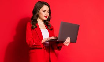 红色背景下手持笔记本电脑的妇女