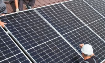两个人站在屋顶上，拿着太阳能板
