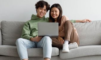快乐的年轻夫妇沙发上使用笔记本电脑