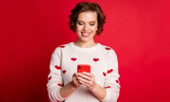 年轻女子与红色背景上的红色的智能手机