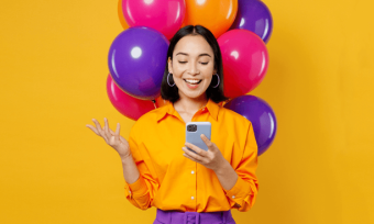 一名拿着手机、用彩色气球庆祝的女子