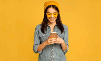 幸福的女人用智能手机黄色背景